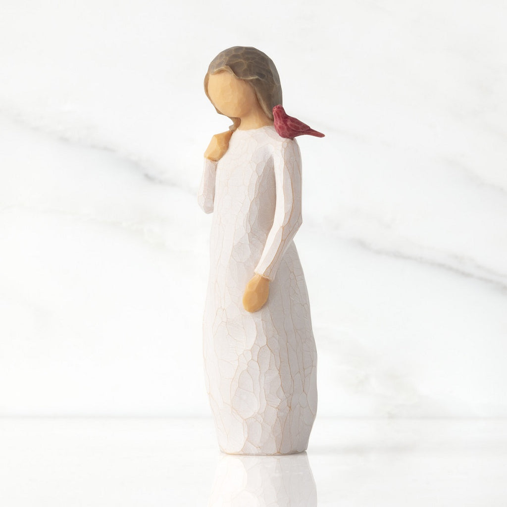 Standing figure in cream dress with red cardinal birch perched on her shoulder
