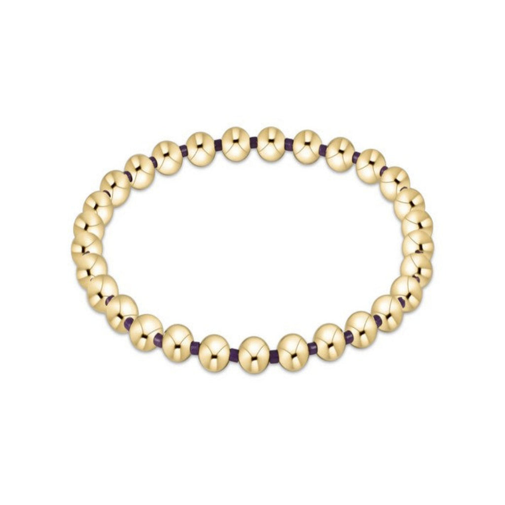 Gold beaded bracelet with purple accents on a white background