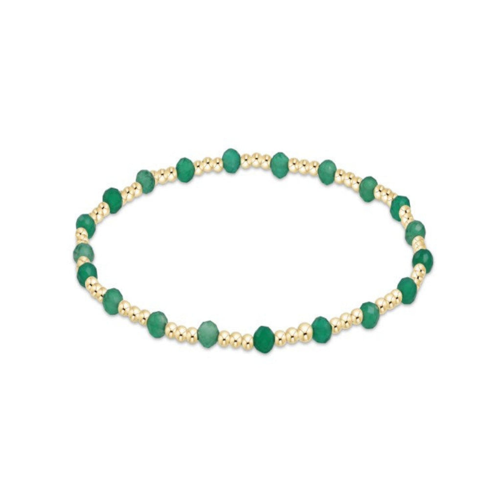 Bracelet with green beads and gold accents on a white background