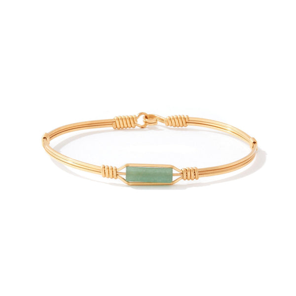 Gold bracelet with a green stone on a white background