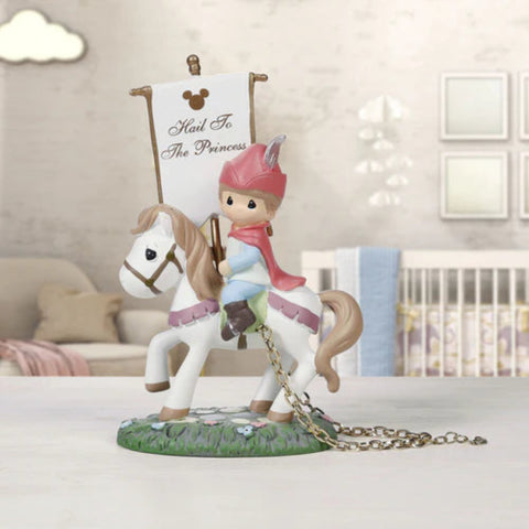 A Precious Moments style figurine of a princess in a pink hat and cape riding a white horse, holding a banner that reads 'Mail To The Princess' with a Mickey Mouse icon. The figurine is displayed on a tabletop with a softly blurred nursery background.