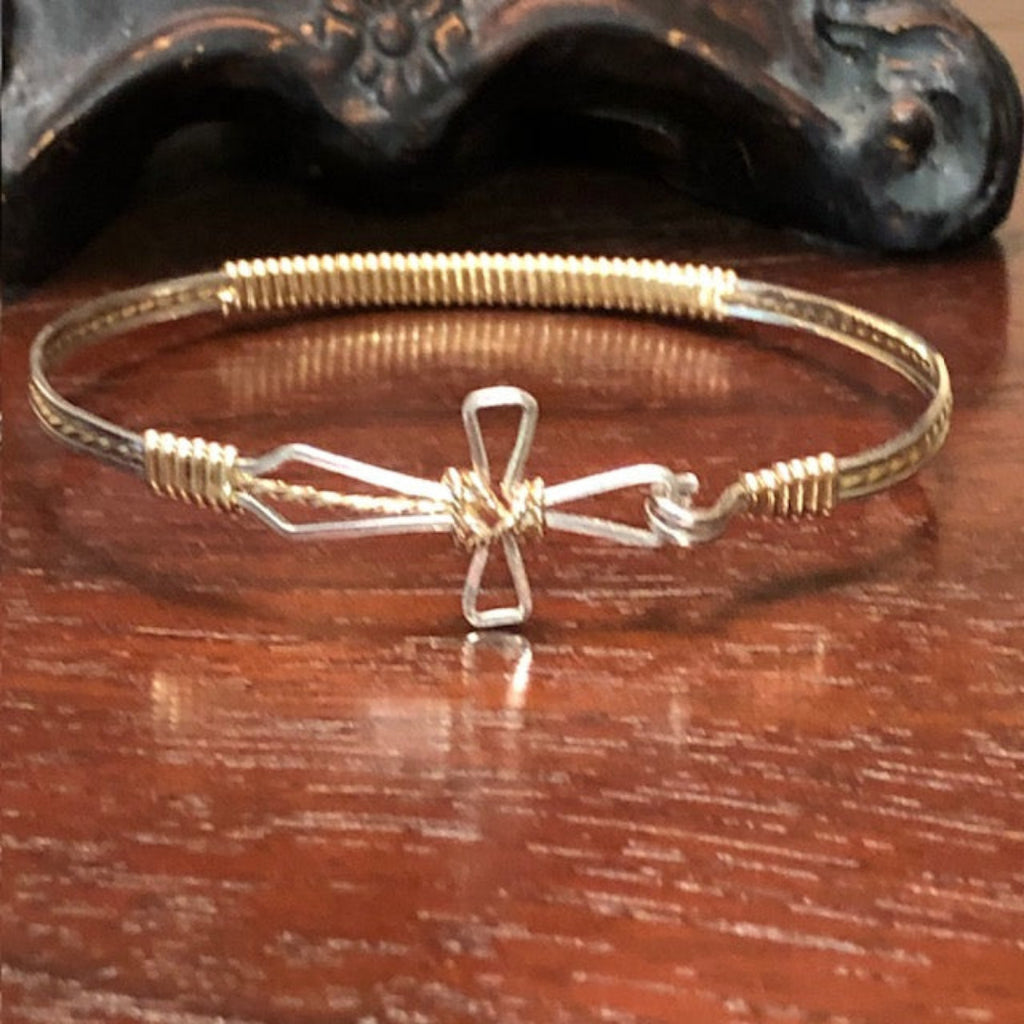 Gold bracelet with a cross design on a wooden surface