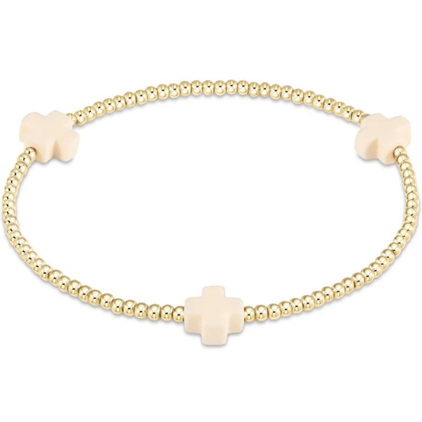 Small Gold beaded bracelet with 3 off white beige crosses on a white background