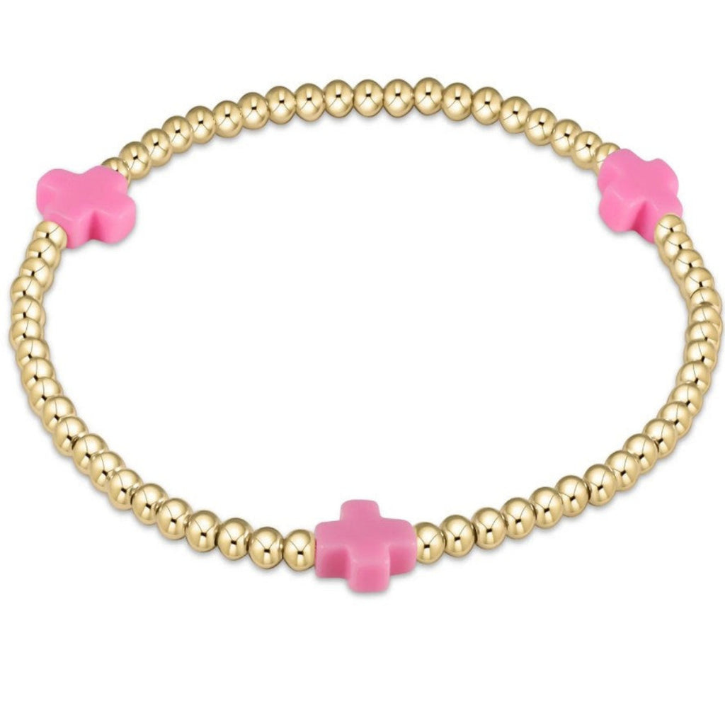 Gold beaded bracelet with 3 pink crosses on a white background