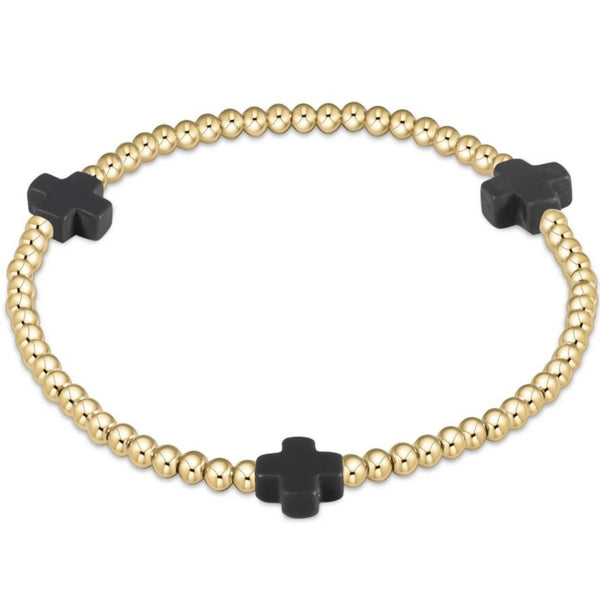 Bracelet with gold beads and 3 charcoal crosses on a white background