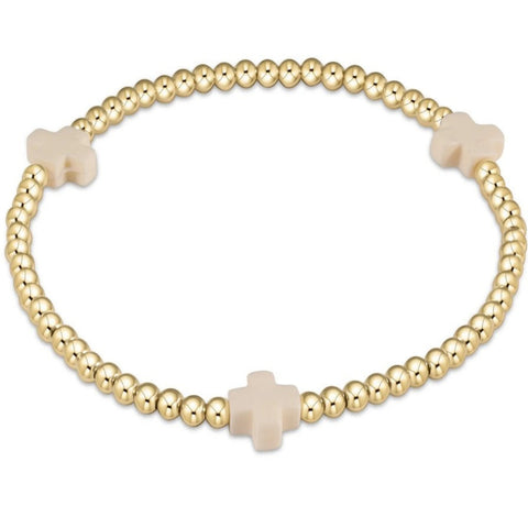 Gold beaded bracelet with 3 off white crosses on a white background
