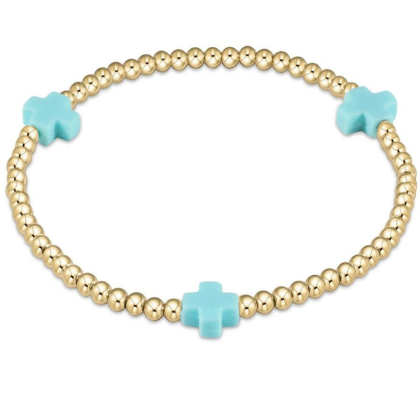 Bracelet with gold beads and 3 turquoise crosses on a white background