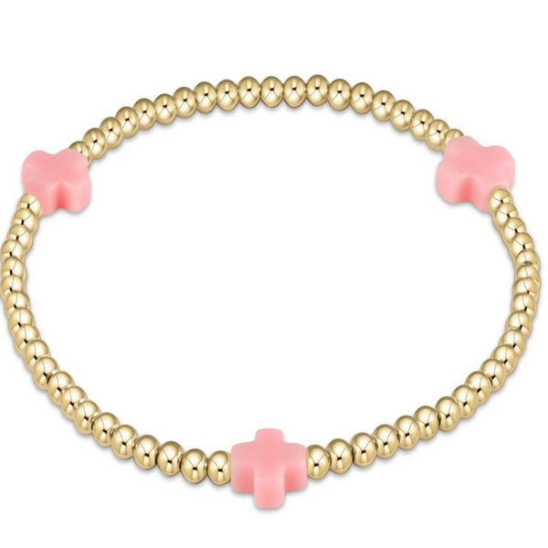 Gold beaded bracelet with 3 light pink crosses on a white background