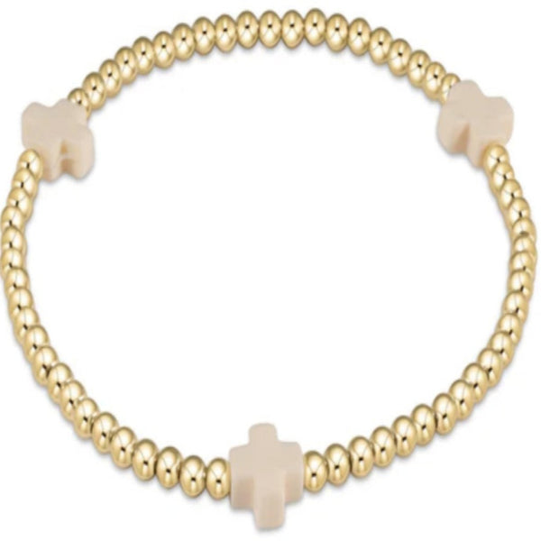 Gold beaded bracelet with e off white crosses on a white background