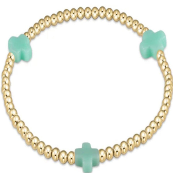 Gold bracelet with 3 minte crosses on a white background