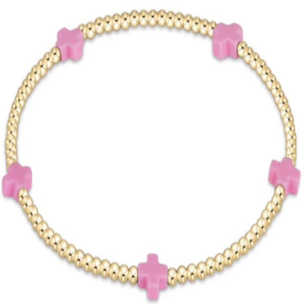 Gold bracelet with light pink crosses on a white background