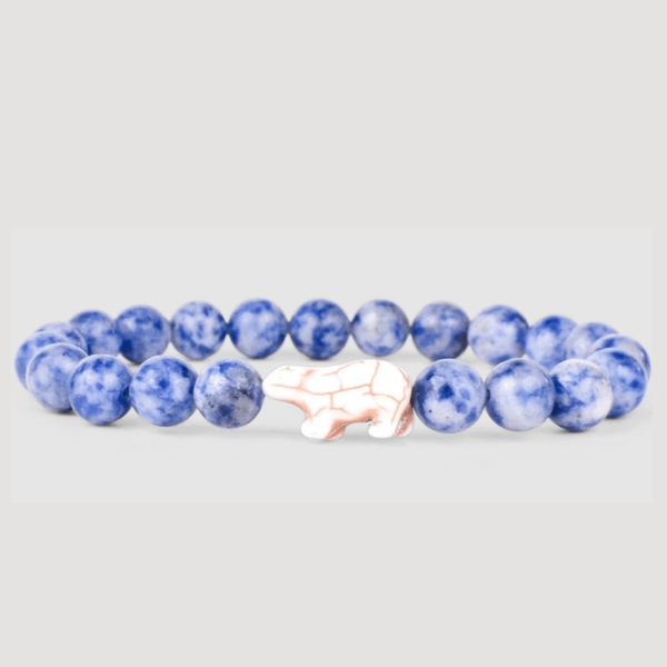 Blue beaded bracelet with a white and gold bear charm on a white background