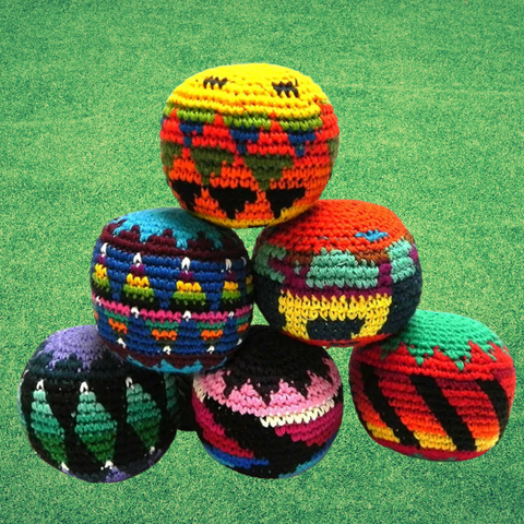 Five colorful hand-crocheted knit balls arranged in a pyramid stack on a green grass-like surface.