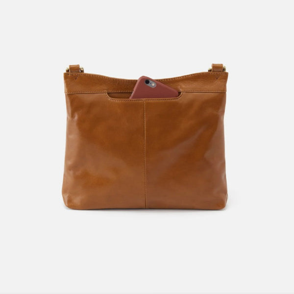 A tan leather shoulder bag with a front pocket holding a burgundy phone, shown against a plain white background.