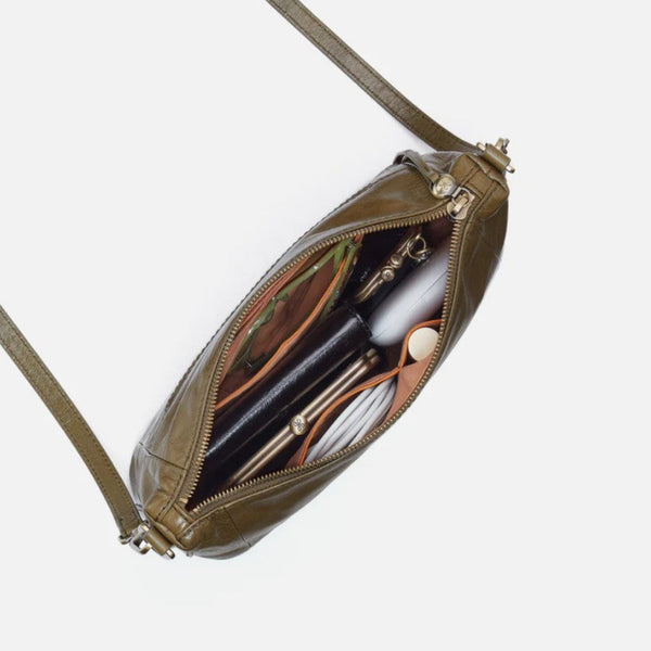 An olive green leather crossbody bag shown open, revealing its interior compartments and contents, set against a plain light gray background.