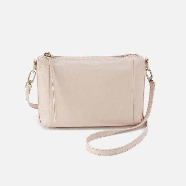 A light beige faux-leather crossbody bag with a top zipper, tassel detail, and a matching adjustable shoulder strap, shown against a plain light gray background.