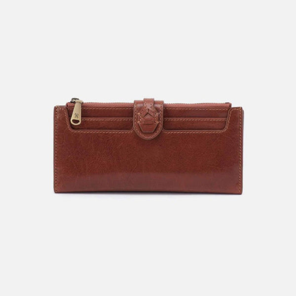 A brown faux-leather zip-around wallet with a decorative strap and gold-tone zipper pull, shown against a plain light gray background.