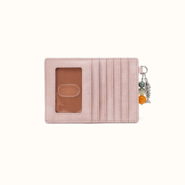 A light pink textured leather card holder wallet with an ID window and a silver keychain charm featuring colorful beads, shown on a plain off-white background.