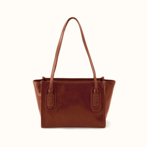 A brown leather tote bag with dual shoulder straps and decorative strap tabs, shown against a plain off-white background.