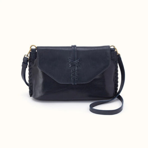 A black leather crossbody bag with a front flap, decorative stitched detail, braided strap edges, and gold-tone hardware, shown on a plain off-white background.