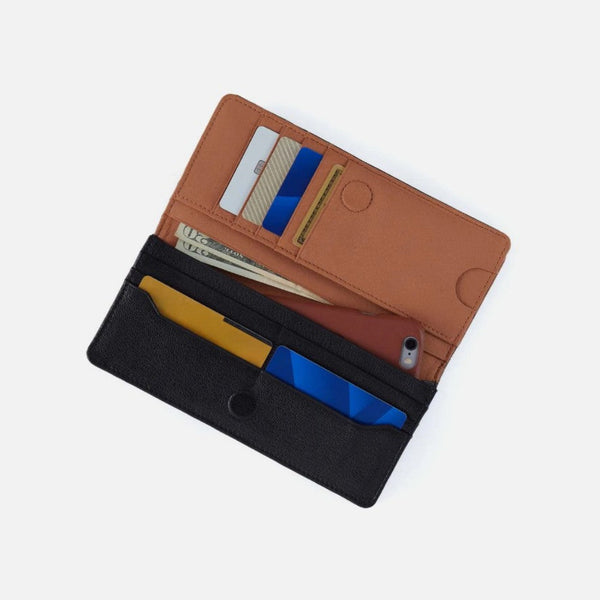 A brown and black multi-compartment wallet shown open, containing credit cards, cash, and a smartphone, photographed on a light gray background.
