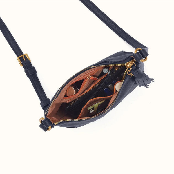 A navy blue leather crossbody bag with gold-tone hardware, shown open to reveal a brown interior organizer. The bag features a matching navy strap with a gold buckle and a tassel zipper pull, photographed on a clean off-white background.
