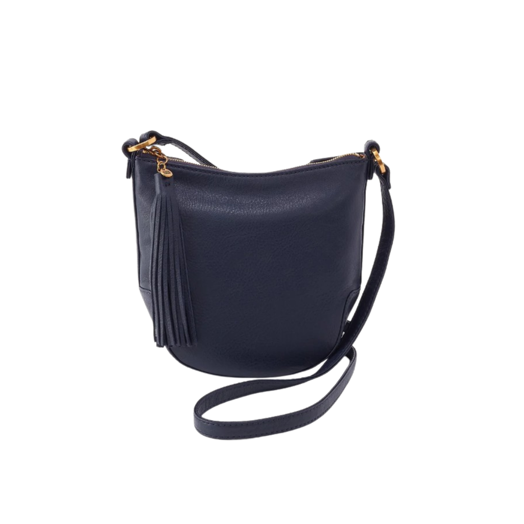 A navy blue pebbled leather crescent-shaped shoulder bag with a gold-tone zipper, a tassel detail on the front, and a thin matching shoulder strap, shown against a plain white background.