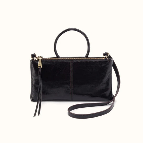 A black leather handbag with a top handle, a long shoulder strap, and a zippered top closure, shown against a plain off-white background.