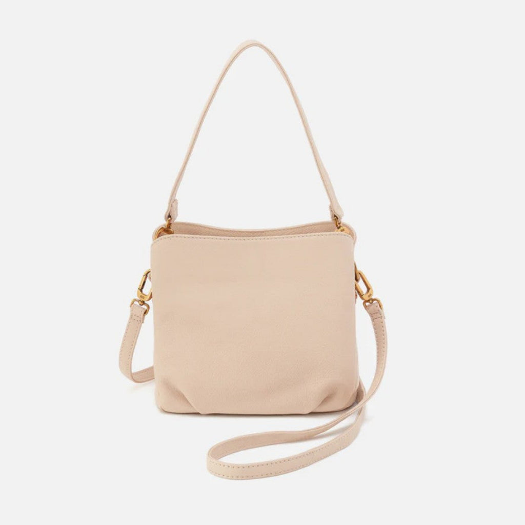 A light beige leather crossbody handbag with a matching shoulder strap and gold-tone hardware, shown against a plain light gray background.