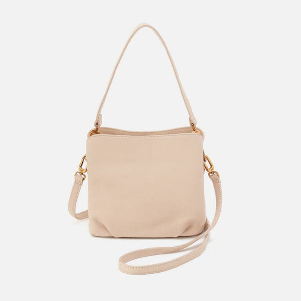 A light beige leather crossbody handbag with a matching shoulder strap and gold-tone hardware, shown against a plain light gray background.