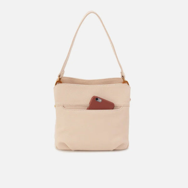 A light beige leather shoulder bag with a single strap and a front pocket holding a brown phone, shown against a plain light gray background.