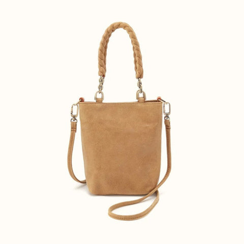A tan suede bucket bag with a braided top handle, a detachable shoulder strap, and silver-tone hardware, shown against a plain off-white background.