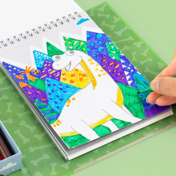 Colorful dinosaur drawing in a notebook with a hand holding a paintbrush.