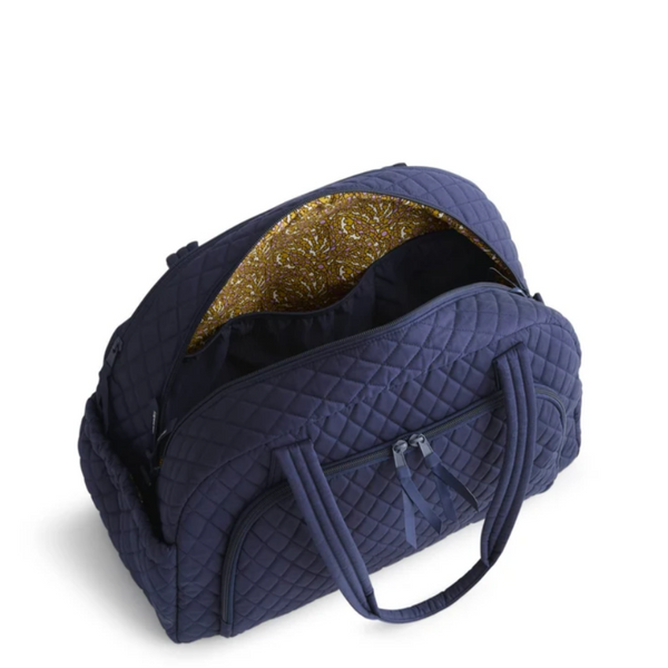 Inside view of a navy blue quilted travel bag with an open top pocket showing a gold glittery interior lining, set against a plain white background.