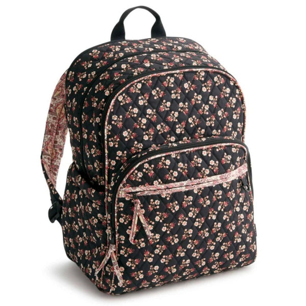 A quilted backpack with a black background and a dense floral print in pink, red, and beige, featuring a front zippered pocket and a top carry handle.