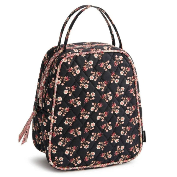 A quilted black backpack featuring an all-over floral print with pink, red, and white blossoms, complete with dual top handles and a matching fabric tassel zipper pull.