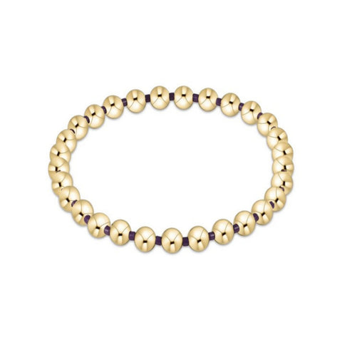 Gold beaded bracelet with purple accents on a white background