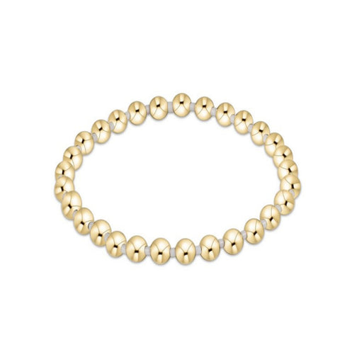 Gold beaded bracelet with white beads on a white background