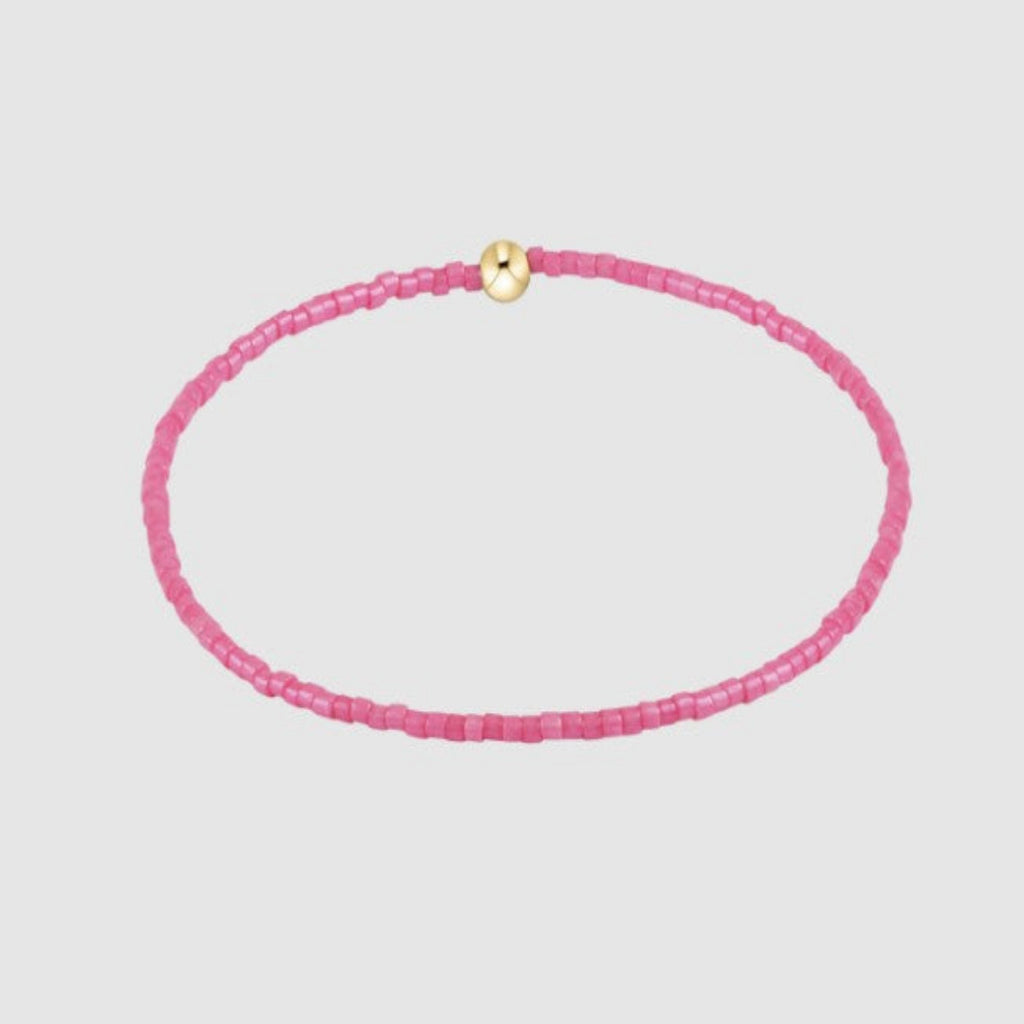 Pink beaded necklace with a gold clasp on a light gray background