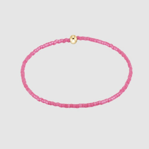 Pink beaded necklace with a gold clasp on a light gray background