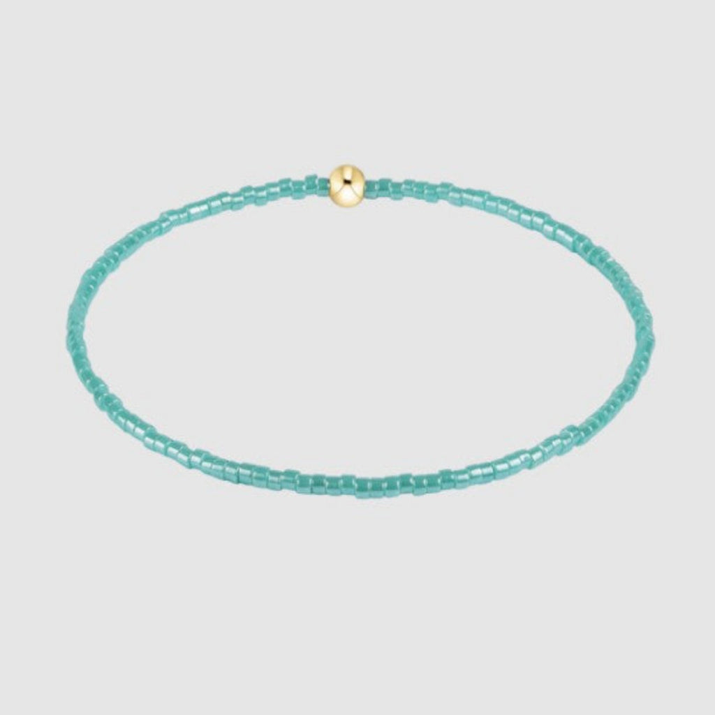 Turquoise beaded necklace with a gold clasp on a light gray background