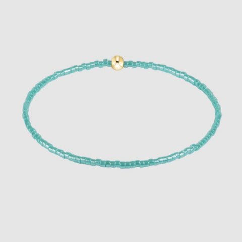 Turquoise beaded necklace with a gold clasp on a light gray background