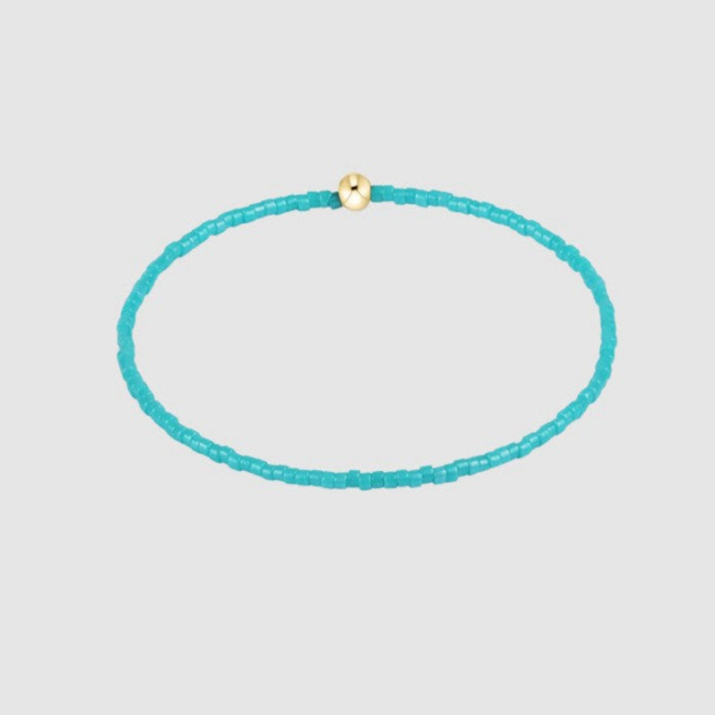 Turquoise beaded bracelet with a gold clasp on a light gray background