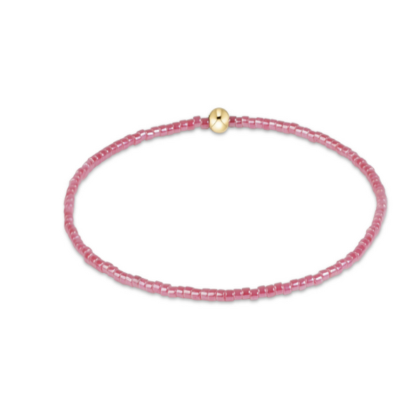 A delicate pink beaded bracelet with a small gold bead accent at the top, displayed on a clean white background.