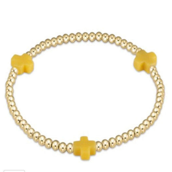 Gold bracelet with 3 yellow cross charms on a white background