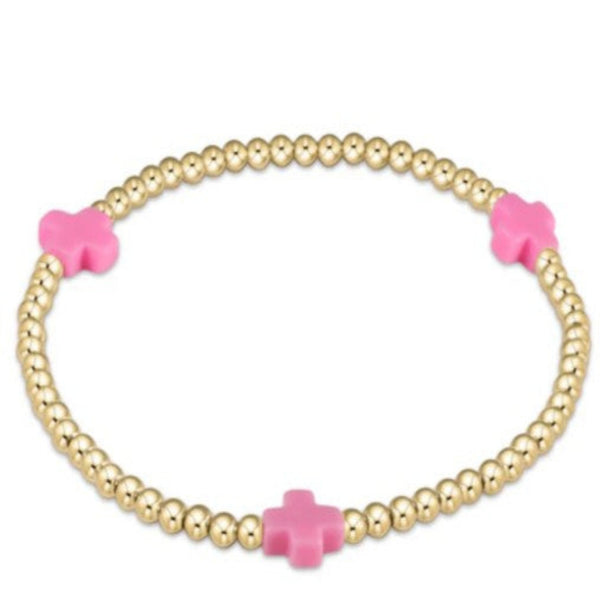 Gold beaded bracelet with 3  pink crosses on a white background