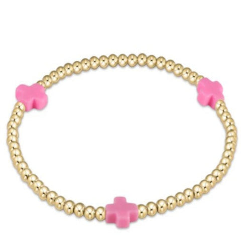 Gold beaded bracelet with 3  pink crosses on a white background