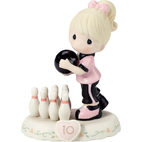 A Precious Moments style ceramic figurine of a young girl bowling, holding a black bowling ball and standing beside a set of white bowling pins on a decorative base with a pink heart-shaped number 10.