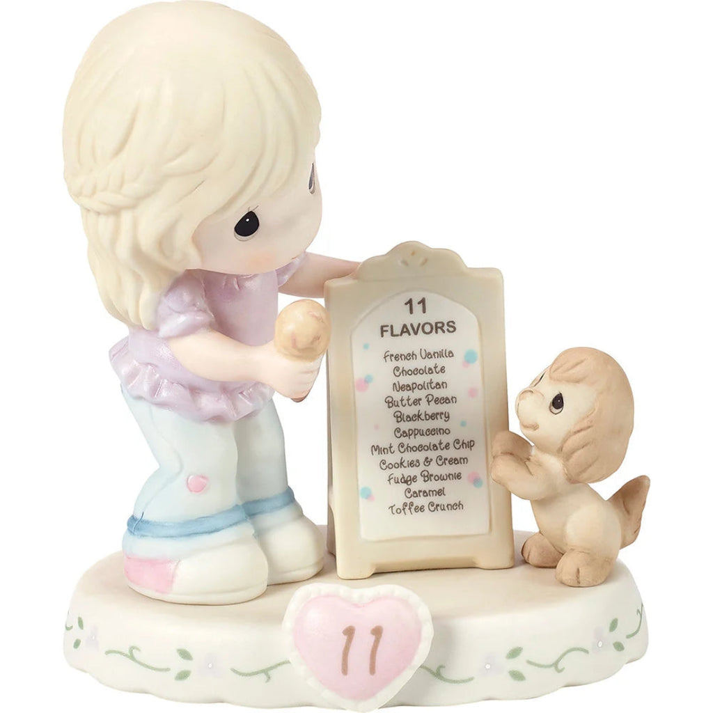 A ceramic figurine of a blonde girl holding a flavor list sign with 11 items, next to a small dog, on a white background.