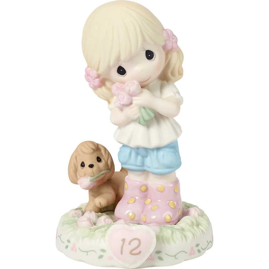 A Precious Moments figurine of a blonde girl holding pink roses next to a small brown dog, standing on a round base with a pink heart that reads '12'.